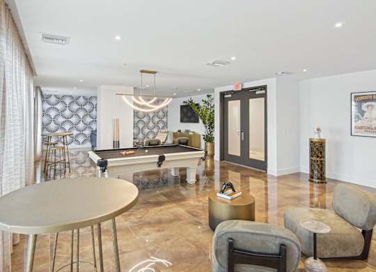 A pool table in our social club with plush seating and a table at Hollywood Heights on the Boulevard Luxury Apartments in Hollywood, FL