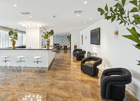 Lobby with dark grey chairs and white barstools next to our social club at Hollywood Heights on the Boulevard Luxury Apartments in Hollywood FL