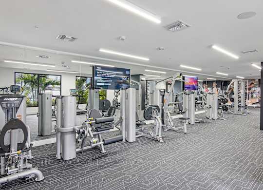 Our gym machines in our state-of-the-art fitness center with 2 large TVs and a mirror wall at Hollywood Heights on the Boulevard Luxury Apartments in Hollywood FL