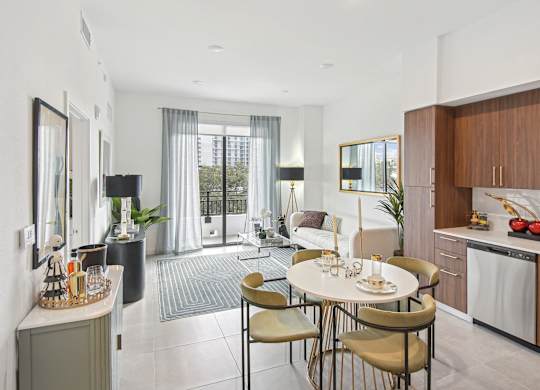 A modern dining room with a table set for two and a kitchen area with wooden cabinets.  A modern kitchen with a dining table and chairs, fridge with a ice maker, stovetop, and microwave  Living room and modern kitchen in our 2-bedroom model with a dining table and chairs  Balcony view of Hollywood Boulevard at Hollywood Heights on the Boulevard Luxury Apartments in Hollywood, FL