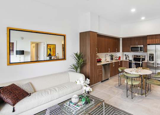 A modern living room with a white couch and a coffee table in front of a large mirror at Hollywood Heights on the Boulevard Luxury Apartments in Hollywood, FL