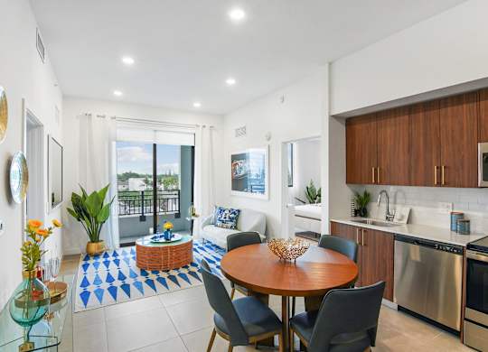 Living room and modern kitchen in our 2-bedroom model with a dining table and chairs  Balcony view of Hollywood Boulevard at Hollywood Heights on the Boulevard Luxury Apartments in Hollywood, FL