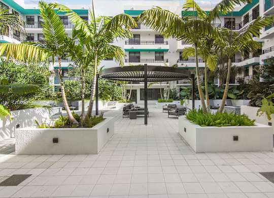 Cushioned patio seating under a circular pergola surrounded by our serenity garden in our courtyard at Hollywood Heights on the Boulevard Luxury Apartments in Hollywood, FL
