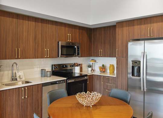 A kitchen with wooden cabinets and a stainless steel refrigerator.