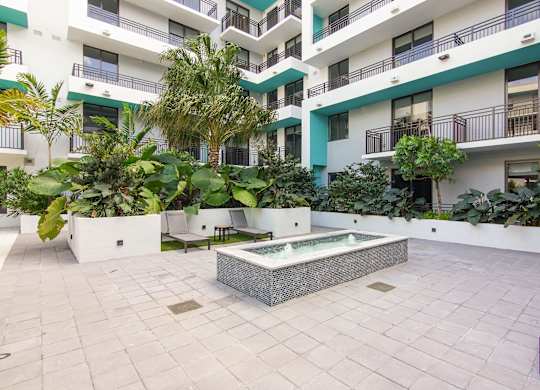 A small fountain surrounded by our serenity garden and lounge chairs at Hollywood Heights on the Boulevard Luxury Apartments in Hollywood, FL
