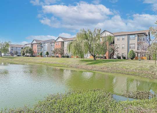 A row of apartment buildings with a pond in front at Ultris Island Park in Shreveport, LA