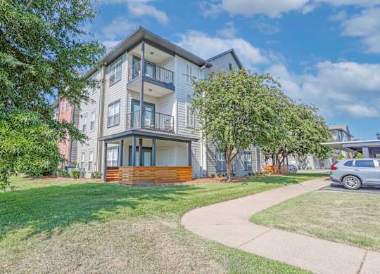View of apartment exterior with patio and balconies and lush landscaping at Ultris Island Park in Shreveport, LA