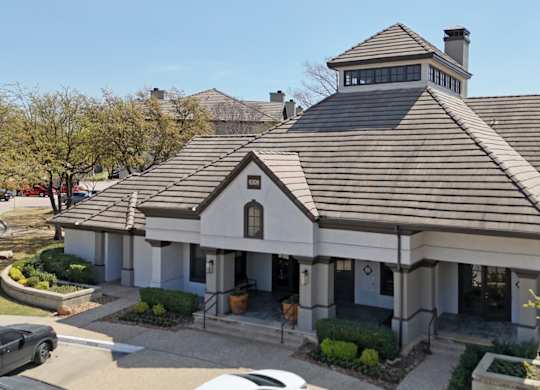 A leasing office with a brown roof and well-trimmed vegetation at Jefferson Place Apartments in Irving, TX