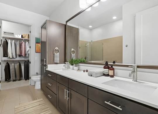 A virtually staged bathroom with a sink, mirror, and a large closet at Knox Heights apartments in Dallas, TX