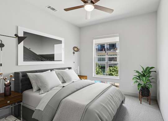 A virtually staged bedroom with a large bed and a ceiling fan at Knox Heights apartments in Dallas, TX