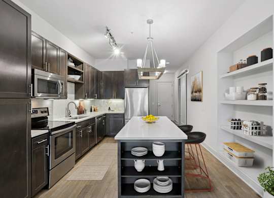 A modern kitchen with dark wood cabinets and a white island at Knox Heights apartments in Dallas, TX