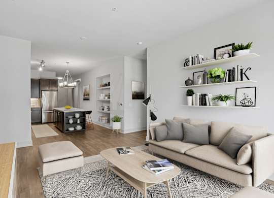 A virtually staged living room with a couch, coffee table, and shelves with plants and picture frames at Knox Heights apartments in Dallas, TX