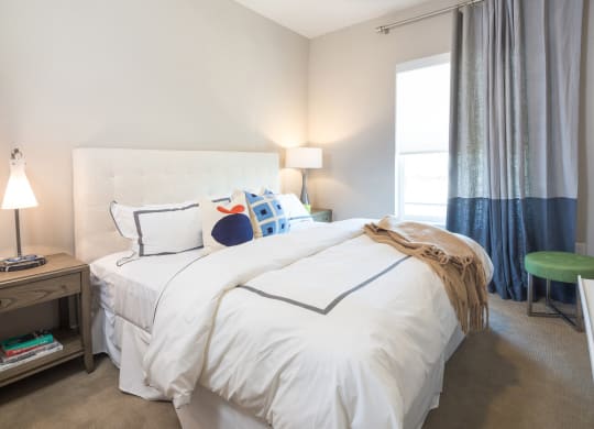 model bedroom with a queen bed and grey and blue curtain