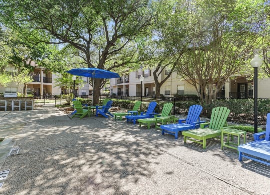 a group of lawn chairs and umbrellas in front of an apartment building