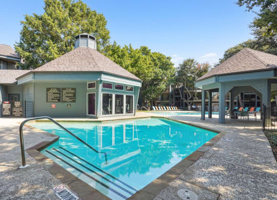 Sparkling swimming pool surrounded by a lush green lawn at Laurels of Sendera apartments in Arlington, TX