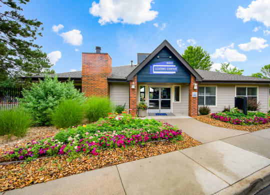 The front the leasing office with colorful flowers and greenery at Greensview Apartments in Aurora, CO