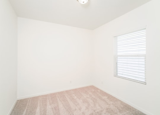 a bedroom with white walls and a window with a blind at Beacon at Bunton Creek, Kyle