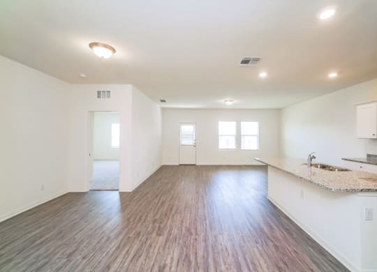 an empty living room and kitchen area with a granite countertop at Beacon at Meridian, Texas