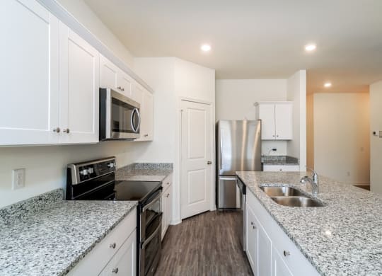 a kitchen with granite countertops and white cabinets at Beacon at Meridian, San Antonio, TX