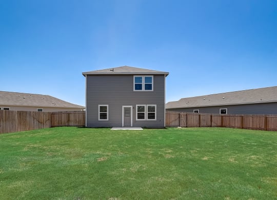 a backyard with a gray house and a wooden fence at Beacon at Meridian, San Antonio Texas