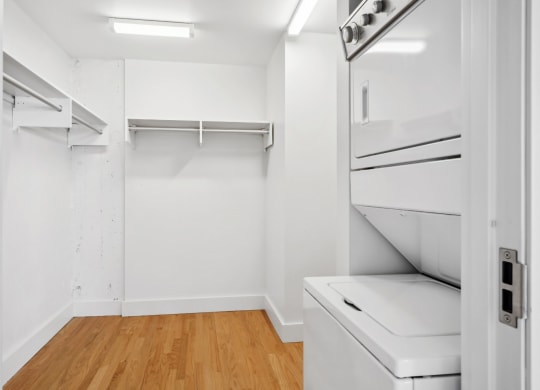 Spacious walk-in closet with a stacked washer and dryer and polished wood floors at Mid Elm Lofts in Dallas, TX