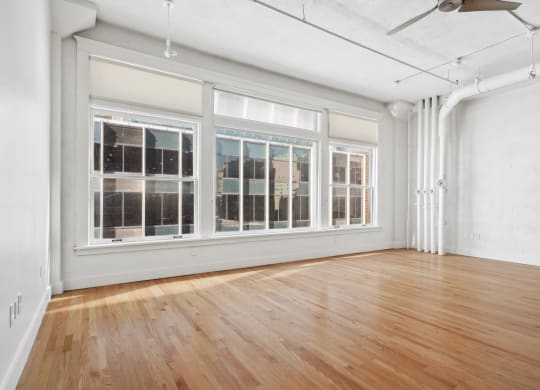 View of large living room with urban accents, polished wood floors and large windows at Mid Elm Lofts in Dallas, TX