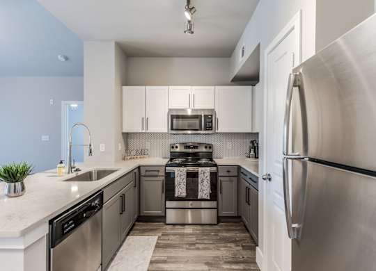 A2 model kitchen with stainless steel appliances, quartz counters, and white cabinets at Asheville at Spring Branch apartments in Houston, TX