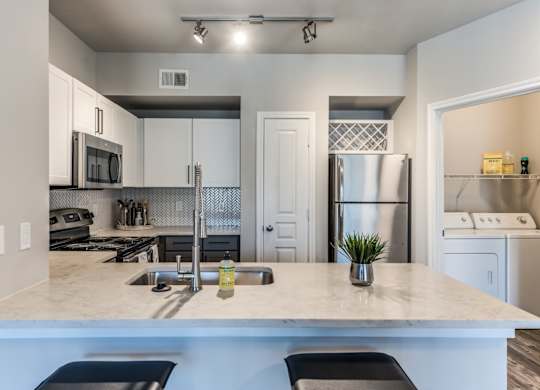 A2 model kitchen with quartz countertops and stainless steel appliances at Asheville at Spring Branch apartments in Houston, TX