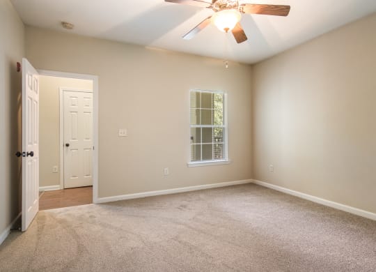 Empty bedroom with soft carpet floor and natural light at Angel Landing apartments in Pensacola, FL