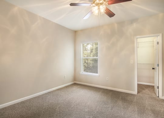 Bright empty bedroom with carpet floor and large windows at Angel Landing apartments in Pensacola, FL