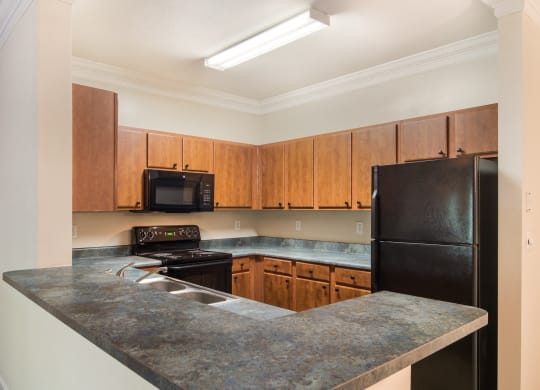 Model kitchen with elevated counter tops and black appliances at Angel Landing Apartment Homes in Pensacola, FL