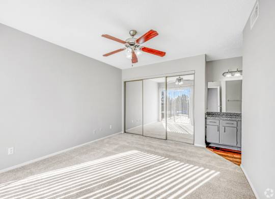 A room with a ceiling fan and a striped rug on the floor.