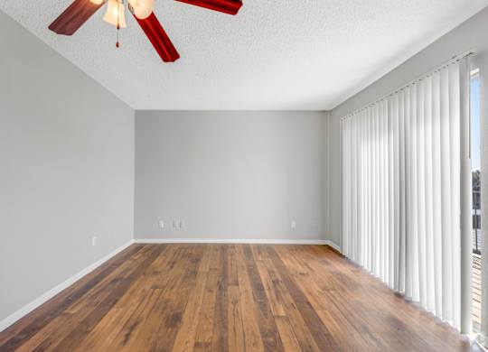 A room with a ceiling fan and wooden flooring.
