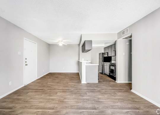 A spacious living room with a kitchen area in the background.