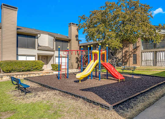 A playground with a slide and a bench at Montfort Crossing Apartments in Dallas, TX.