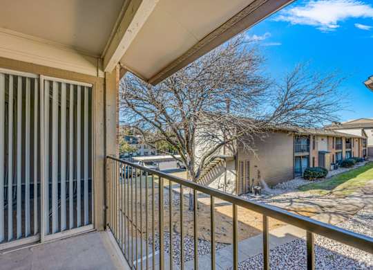 A balcony with a metal railing and a view of apartment buildings.