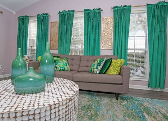 A clubhouse with a grey couch and green curtains at The Marq in Shreveport, LA