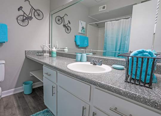 A cypress bathroom with a white toilet and a grey counter top at The Marq in Shreveport, LA