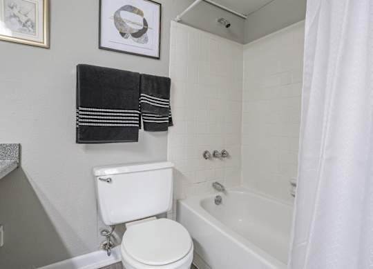 A white toilet sits next to a bathtub in a cypress bathroom at The Marq in Shreveport, LA