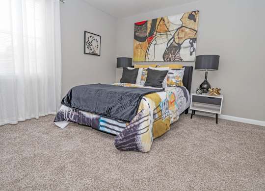 A cypress bedroom with a bed, a nightstand, and a painting on the wall at The Marq in Shreveport, LA