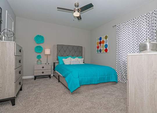 A bedroom with a bed, dresser, and ceiling fan at The Marq in Shreveport, LA