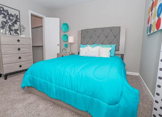 A bed with a turquoise comforter is in the center of a cypress bedroom at The Marq in Shreveport, LA