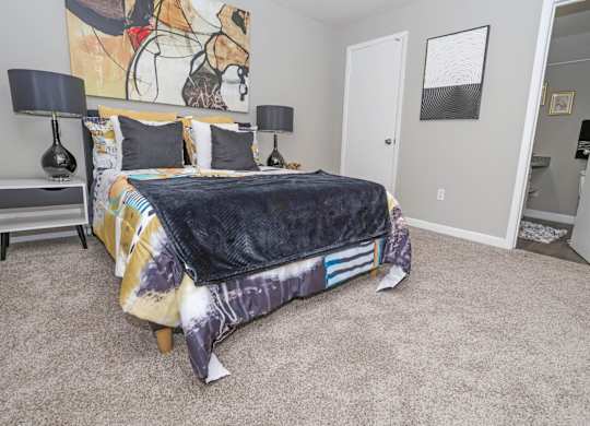 A cypress bedroom with a bed, two lamps, and a painting on the wall at The Marq in Shreveport, LA