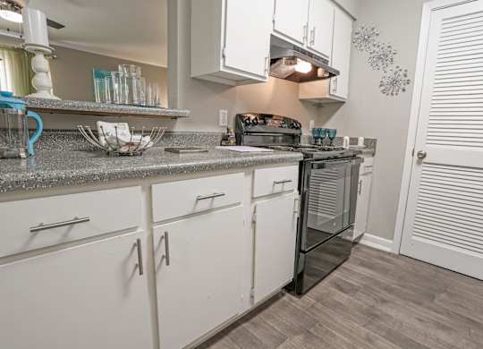 A cypress kitchen with white cabinets and a grey counter top at The Marq in Shreveport, LA