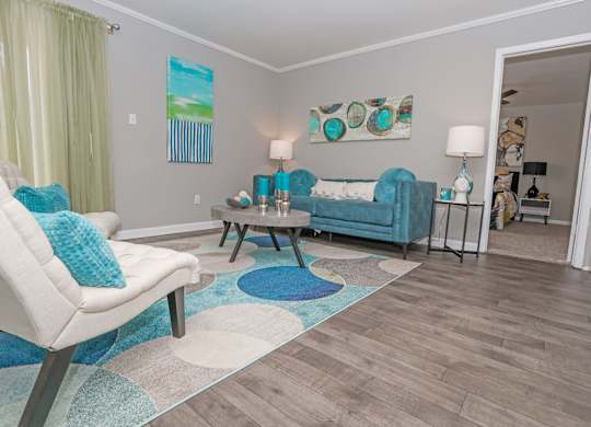 A cypress living room with a white chair and a blue couch at The Marq in Shreveport, LA