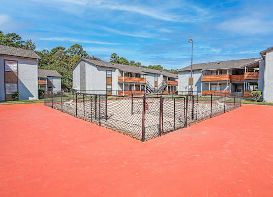 A fenced dog yard with apartment buildings in the background at The Marq in Shreveport, LA
