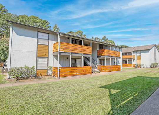 A modern two-story apartment building with a white exterior and wooden accents at The Marq apartments in Shreveport, LA
