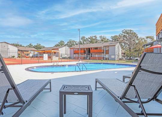 A pool surrounded by chairs and a table at The Marq apartments in Shreveport, LA
