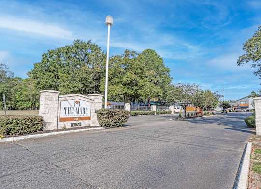 The entrance to The Marq residential complex is surrounded by greenery at The Marq apartments in Shreveport, LA