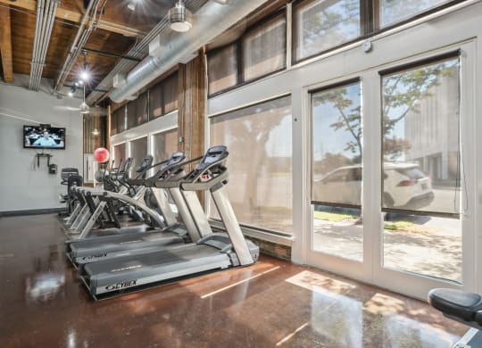 Murray Building gym equipped with cardio equipment and large windows | Deep Ellum Lofts in Dallas, TX